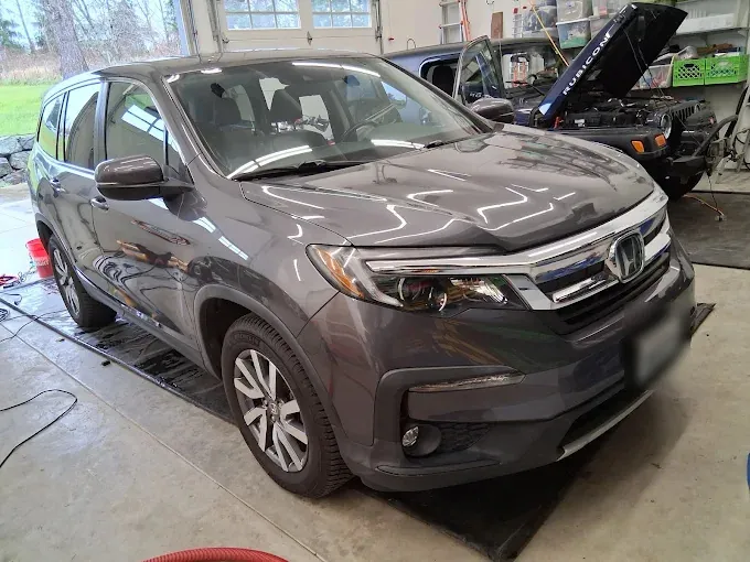 Gray Honda Pilot with its hood open, detailed in the owner's own garage