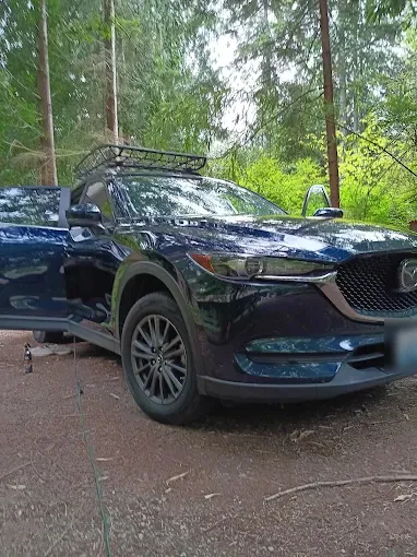 Blue Mazda CX-5 on a dirt driveway in the trees after a detail
