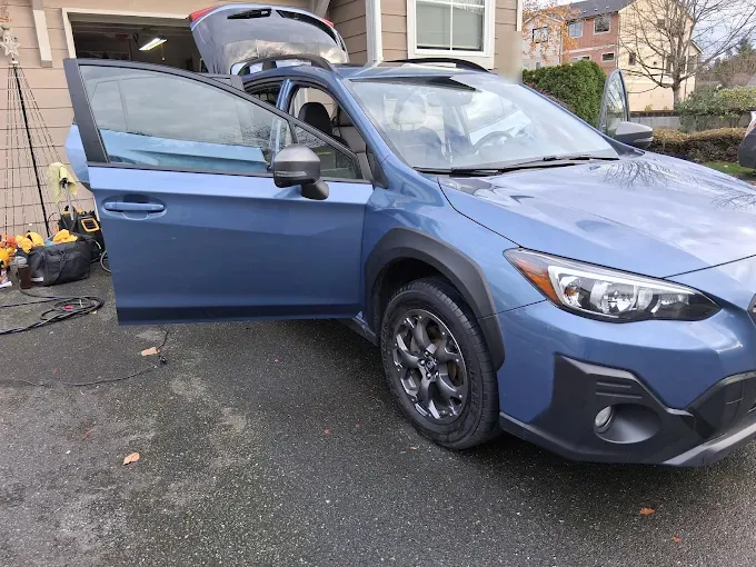 Blue Subaru Crosstrek in a driveway, doors and hood open partway through a detail