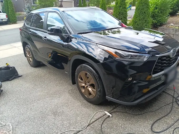 Black Toyota Highlander in its driveway after a full detail, cords still out